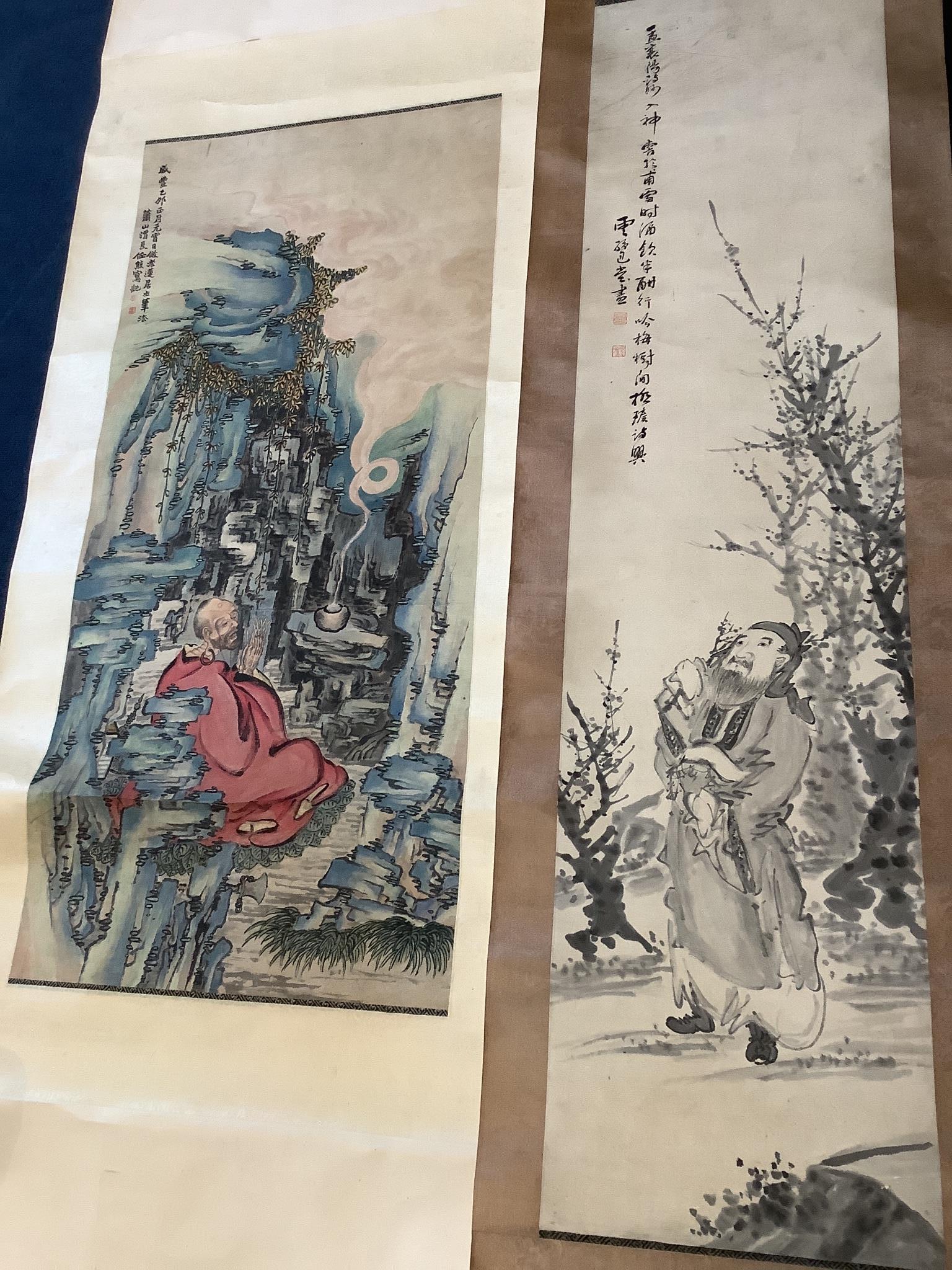 Two Chinese scroll paintings on paper, 20th century, depicting a Luohan in a cave and a scholar amid prunus Images 103 cm X 47 cm and 132 cm X 32.5 cm